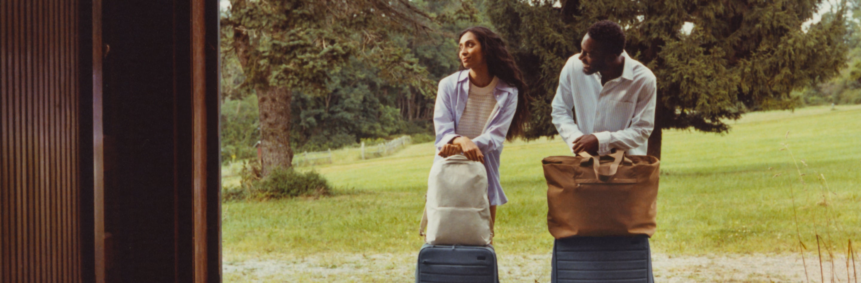 A man and woman standing outside an vacation cabin with two sets of Away luggage