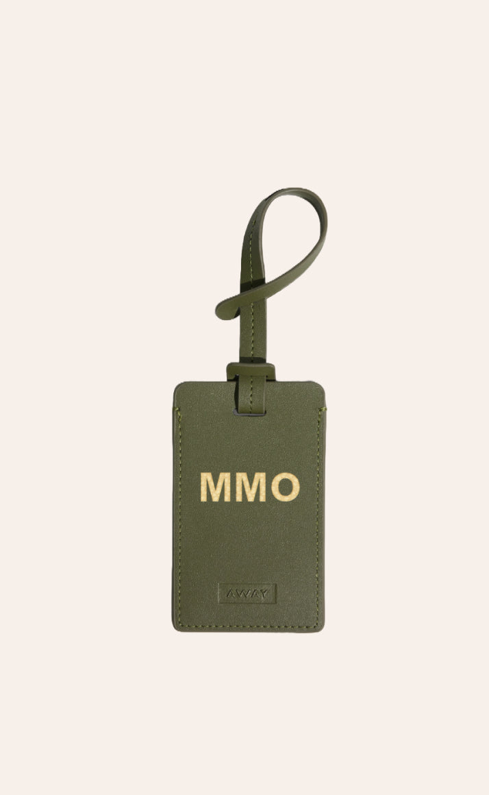 A green Away luggage tag with initials foil stamped on it