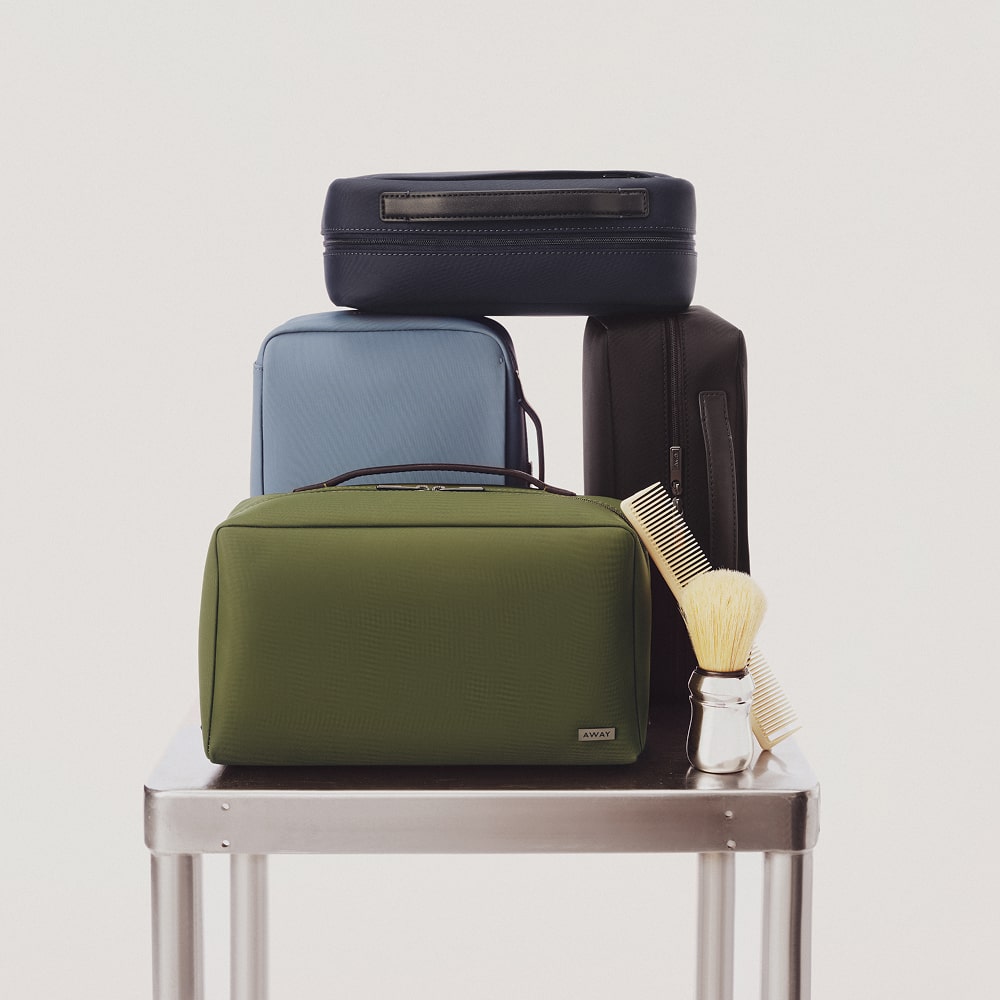 A group of 4 Away toiletry bags, cosmetic cases, and tech cases in various colors on a white background